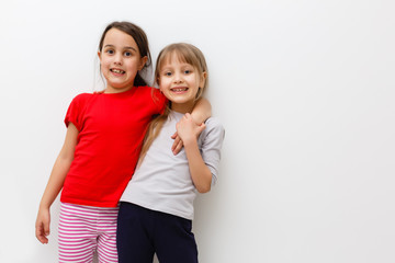 Cute little caucasian girls are keeping hands up, looking at camera and smiling, isolated on a white background