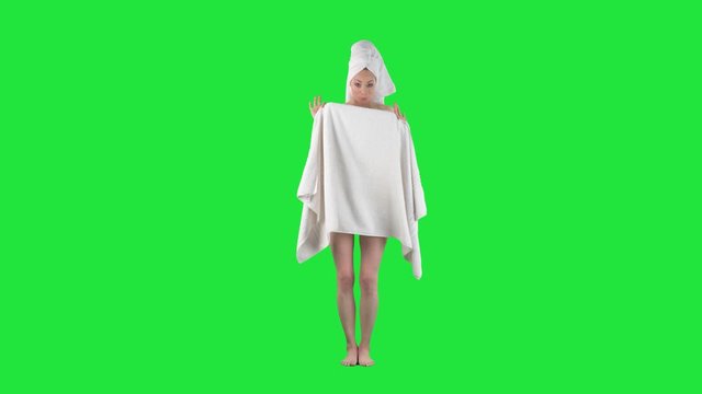 Young nude woman hiding and covering while holding white blank towel with copy space. Full body pre keyed on chroma green screen background. 
