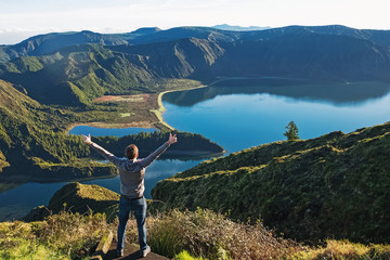 Man traveller standing with the view to the mountain lake