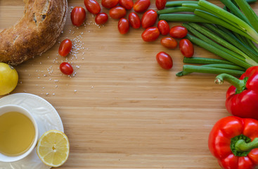 Cherry tomatoes, onions, bread, tea, lemon, peppers, arranged in a circle on a bamboo sheet. Healthy breakfast ingredients on the table. Kitchen composition before cooking, preparation.