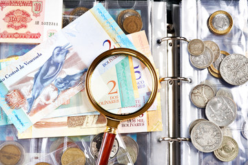 Coins and venezuelan notes with magnifying glass