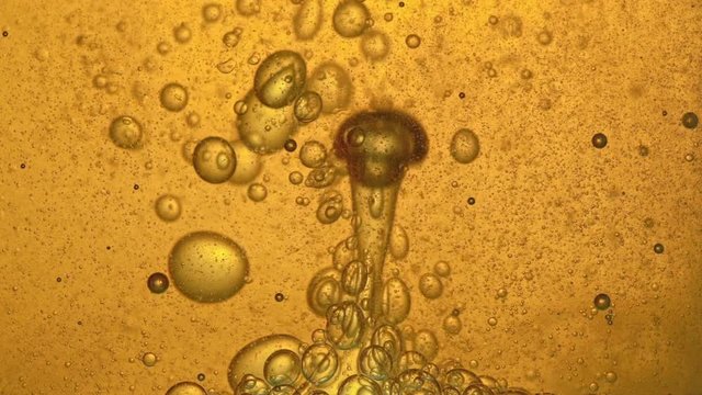 Fuel, oil, yellow golden hue, with moving bubbles, up and down, in the glass vessel of the laboratory. Copy space.