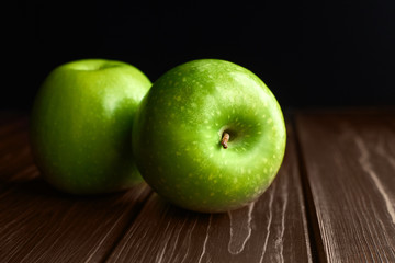 Ripe green apples on dark rustic woden background.