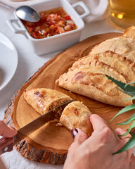 Cutting with a knife Empanadas argentinas traditional food with sauce on wooden ray