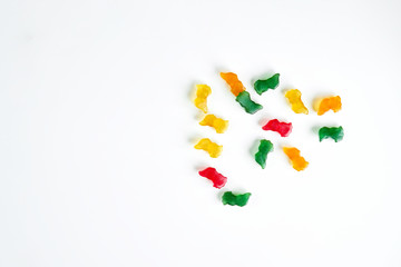 Yellow, green, red and orange chewing vitamins on white background. Copy space.