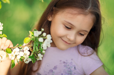 Fototapeta premium little girl with long hair near a flowering tree in nature