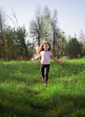 Obraz na płótnie Canvas little girl runs in the meadow in summer