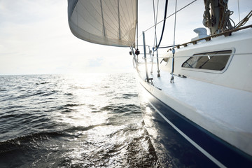 Blue yacht sailing in an open sea on a sunny summer day. Close-up view from the deck to the bow and...
