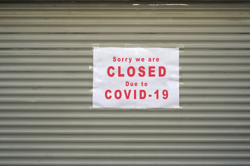 Closeup of information sign on the metallic shutter of the store front : Sorry we are Closed due to covid-19