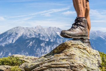 leather hiking shoe of a man stepping on a small rock in the Ziller Valley, Austria. Reaching the peak with a beautiful alpine mountain range in the background