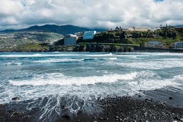 The coast of the island of Tenerife. Tourist season on a tropical island. Volcanic beaches and black sand in Spain. Rocks and rocks in the Atlantic ocean. Trekking and excursions in the Canary Islands