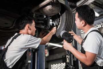 Two mechanic was checking the car suspension.