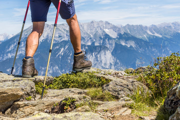 Close up of muscular and veiny male legs with trekking sticks for Nordic walking against the...