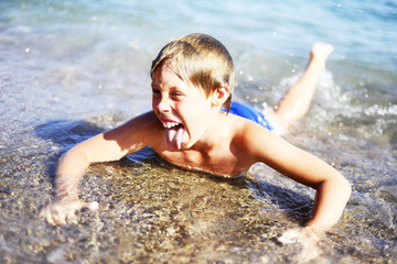  Emotions The boy lies in shallow water in the sea cheerful contented. Laughs. The boy is in a good mood. Holidays. Copy space.