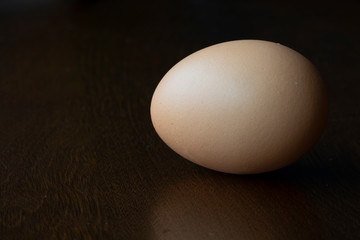 An organic, raw, brown egg on a brown tabletop