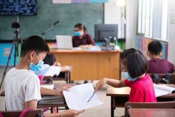 school kids with protection face mask against flu virus at lesson in classroom