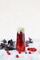homemade raspberry vinegar with purple basil and garlic. In a bottle on a light background. copy space