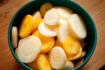 Sliced Carrots in a Small Blue Bowl on a Wood Board White Yellow Orange Multi Colored