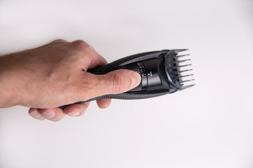 male hand holds a black trimmer in his hand on a white background