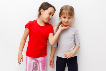 Cute little caucasian girls are keeping hands up, looking at camera and smiling, isolated on a white background