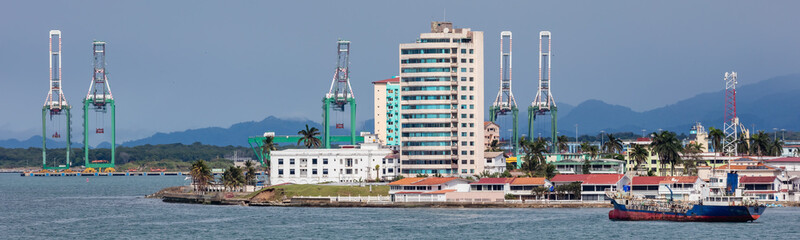 Panoramic view of a port in Panama next to Panama canal. Massive shipyard cranes and buildings in the background, fuel tanker in the foreground.