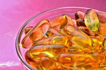 omega 3 capsule. In a glass bowl on a colored background.