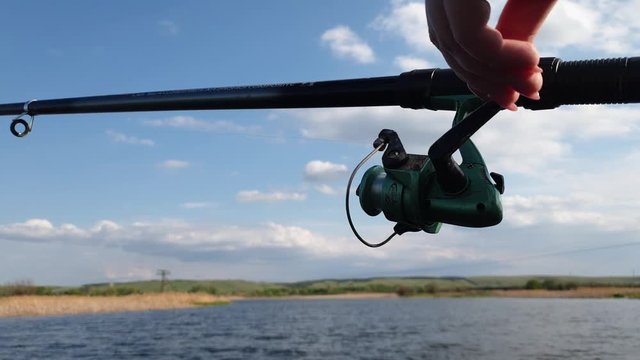 fishing on a reservoir, a woman's hand twists a non-inertia fishing reel, fish fishing