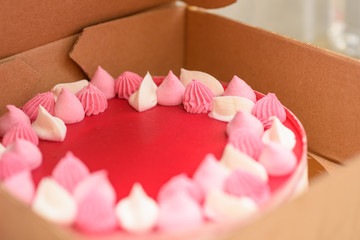 Pretty pink cake in delivery box. Sweet dessert with buttercream.