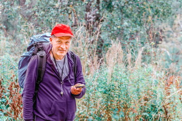 Mature man A tourist with a backpack walking in the forest is guided by the navigator.