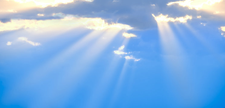 The sun's rays break through the blue clouds. The background of the sky.