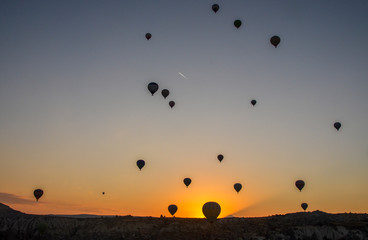 The sunrise in the mountains with Hot air balloons flying over Cappadocia red valley in the sky. Travel to Goreme, Turkey