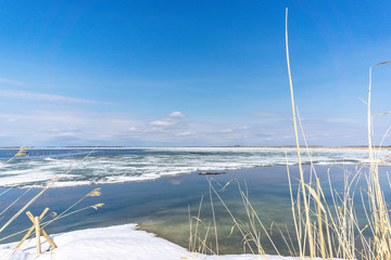 landscape of the frozen river winter lake. water melts snow, the beginning of spring