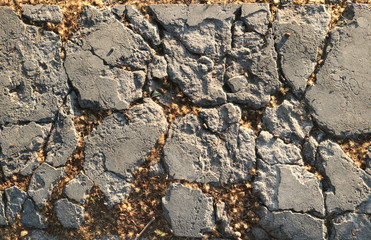 old cracked and broken silver stone surface in the ground with brown polen in the wholes- rough urban texture background for a wallpaper