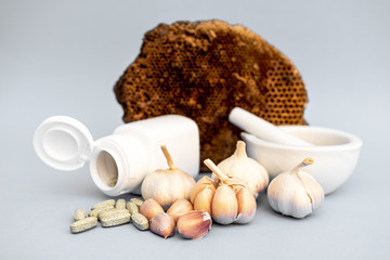 Fototapeta na wymiar Garlic, Medicine grinding cup, Garlic tablet, White medicine bottle on gray background. Alternative medicine, herbal treatment concepts