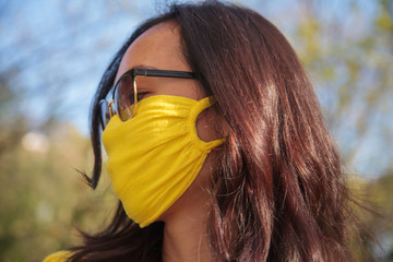 A woman wearing a yellow mouth protection mask and sunglasses
