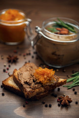 A slice of bread with poultry pate and orange gam, glass jar with poultry pate, decorated with...