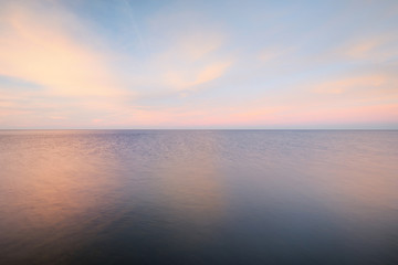 Baltic sea under the colorful sunset sky. Stunning seascape. Golden sunset light through the pink...