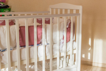 Obraz na płótnie Canvas Baby bed crib with white and Burgundy color pillows with laces