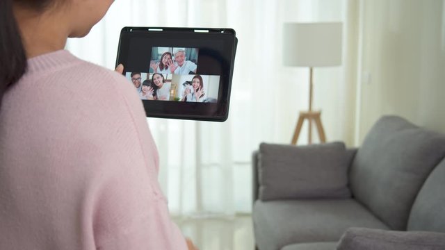 Asian woman talking with family on video call webcam in living room at home while working from home. Self-isolation, social distancing, quarantine for protection coronavirus in next or new normal.