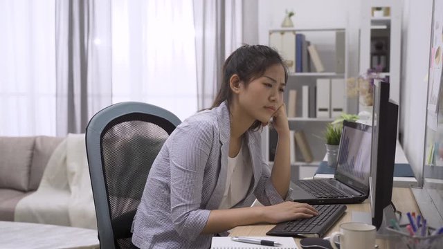 Young Asian japanese businesswoman frowning with concern and trying to understand something while reading on computer monitor. thoughtful office lady thinking solution on project problem in workplace