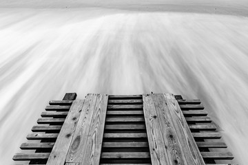 Une jetée et des vagues défoncées avec une longue exposition, photo en noir et blanc