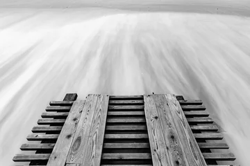 Photo sur Plexiglas Noir et blanc Une jetée et des vagues défoncées avec une longue exposition, photo en noir et blanc