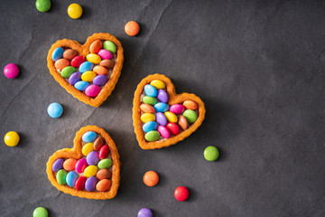 Colorful Candy Buttons on Heart shaped cake on black slate Background - Birthday concept Background