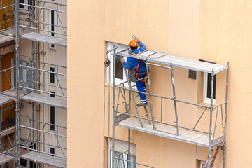 obreros en un andamio reparando una fachada 