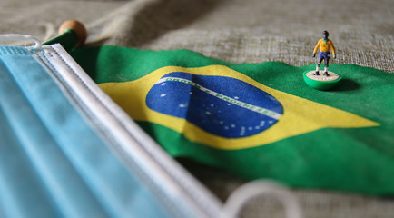 flag of Brazil with plastic football player and surgical mask for Coronavirus Prevention - Covid19 pandemic