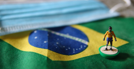 flag of Brazil with plastic football player and surgical mask for Coronavirus Prevention - Covid19 pandemic