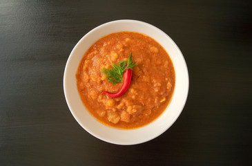 Famous traditional Arabic cuisine - peeled fava beans with chili in white bowl on dark wooden background. Top view. Foul Mudammas, egyptian beans.