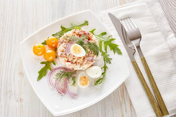 Tuna salad with rice, arugula and tomatoes on light wooden background. Healthy food, seafood menu,