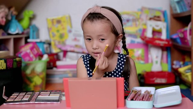 Child make up,Asian little girl is applying eyeshadow make up and painting face ,Happy child making experiments with cosmetics of mother at home