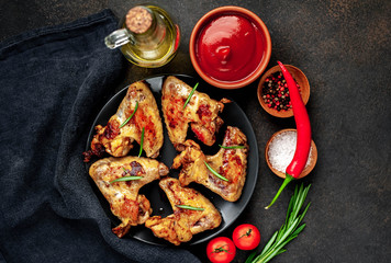 Grilled chicken wings on a plate with spices on a stone background 